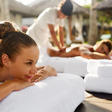 Relaxing outdoor massage scene with two individuals receiving professional treatments in a serene, natural setting, highlighting the tranquil atmosphere and rejuvenating experience.