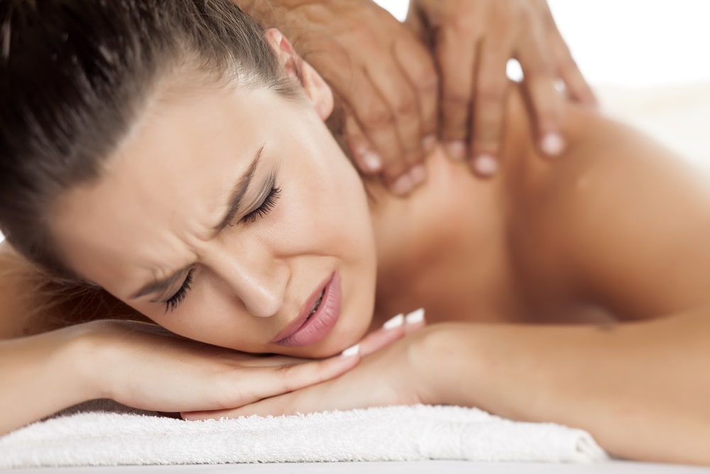 A woman on a massage table feeling some pain during a deep tissue massage.