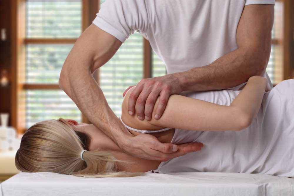 Woman lies on chiropractic table and receives a chiropractic adjustment from a chiropractor