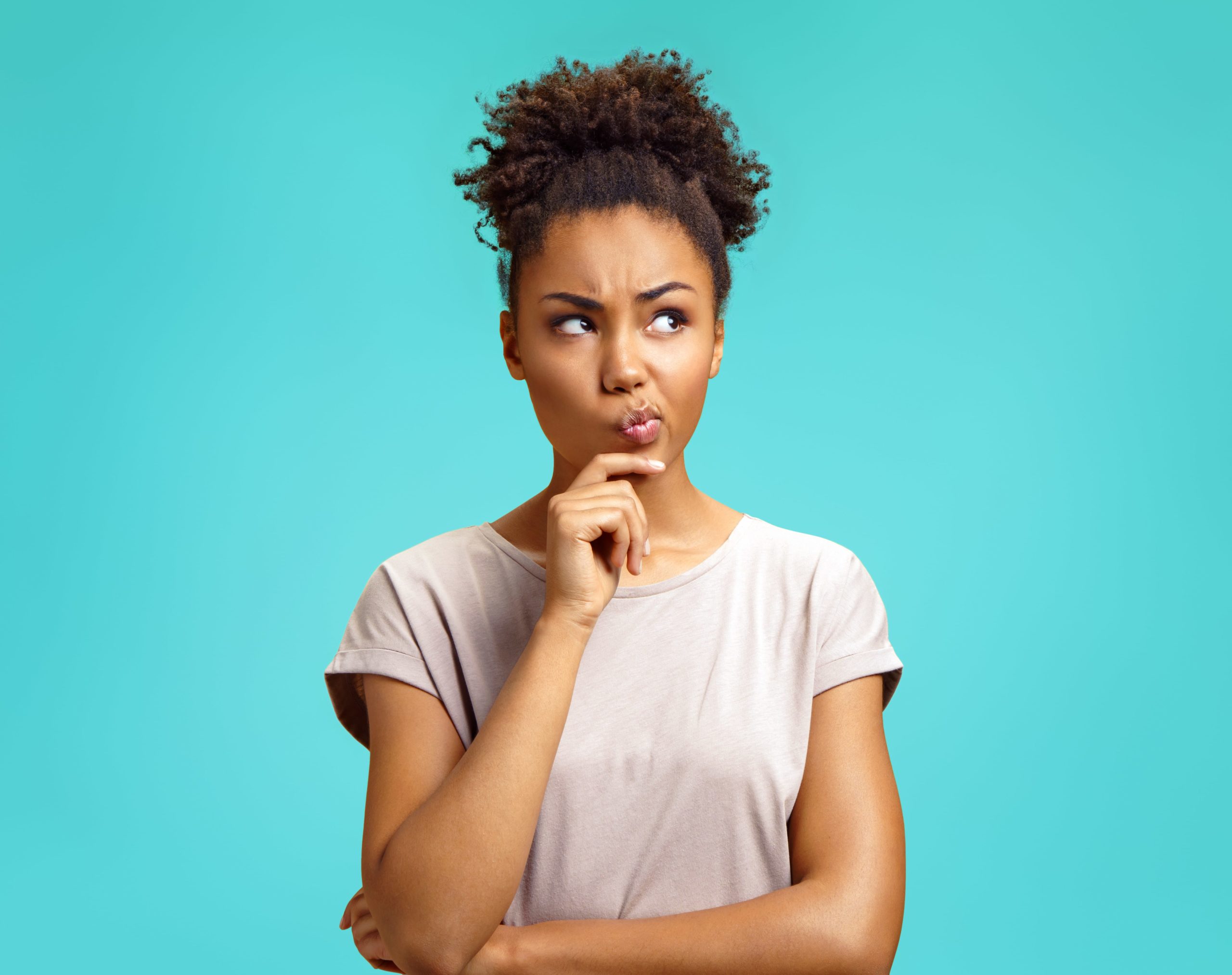 Woman with hand on face thinking in front of a blue background