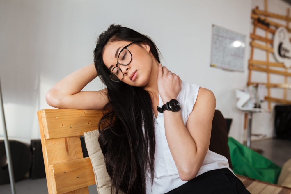 Woman sitting in chair with neck pain from stress