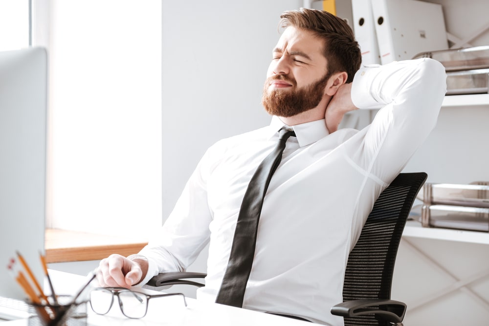 Man sitting at desk grabbing his neck