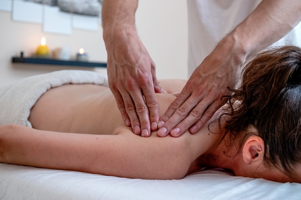 Massage therapist pressing his hands on a woman on a massage table