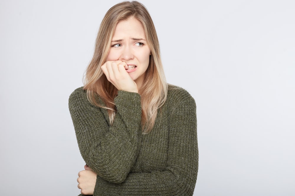 Woman in green sweater biting her nails