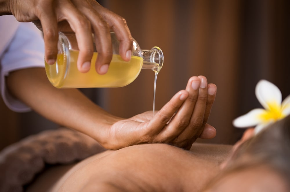 Massage therapist putting massage oil in their hand for use on a massage client