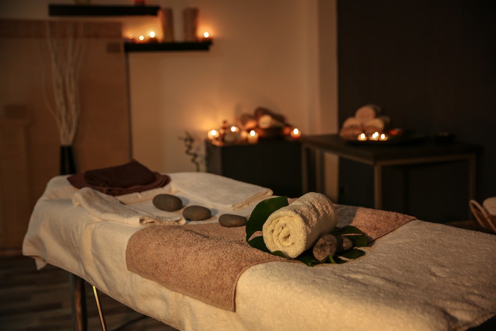 Neatly prepared massage table in the middle of a candle lit massage room