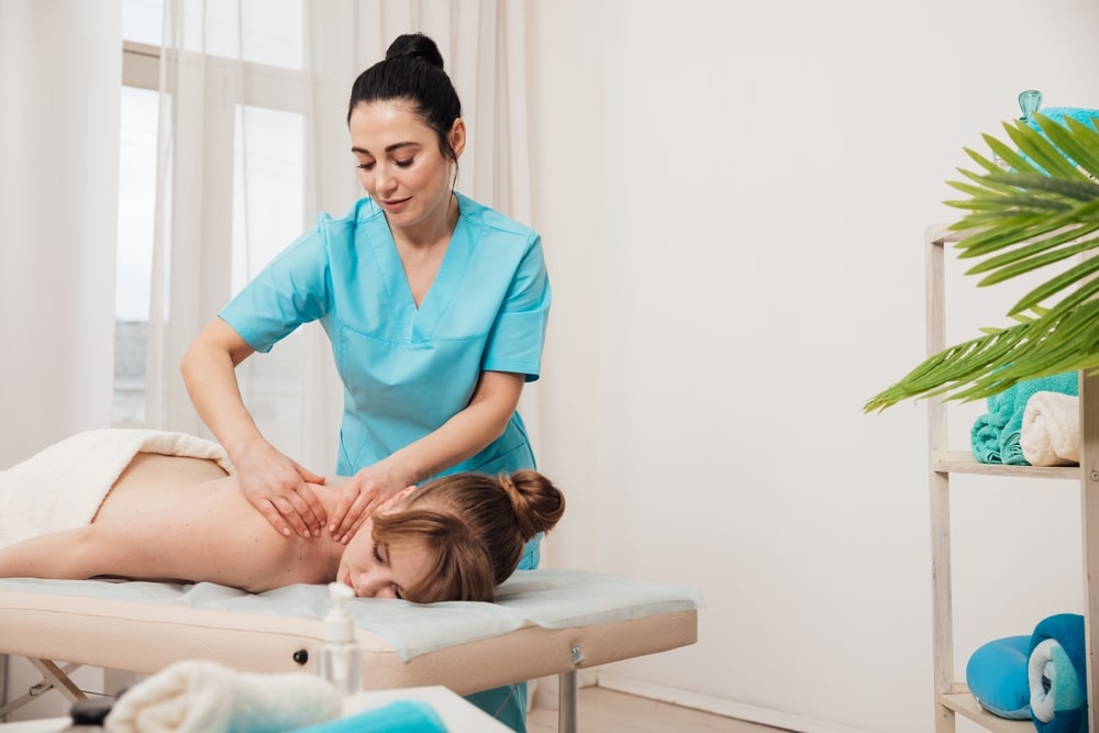 Female massage therapist giving massage to a woman on a massage table